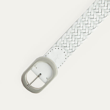 Close-up of the white Twelve Strand Braided Belt's brushed silver oval buckle and keeper loop, showing the embossed Will Leather Goods dog logo and twelve-strand braid detail.