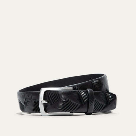 Will Leather Goods Wave Embossed Belt in black, coiled flat showing the wave-textured embossed leather and brushed silver buckle, on a white background.