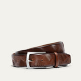 Will Leather Goods Wave Embossed Belt in cognac brown, coiled flat showing the wave-textured embossed leather and brushed silver buckle, on a white background.