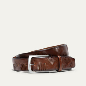 Will Leather Goods Wave Embossed Belt in cognac brown, coiled flat showing the wave-textured embossed leather and brushed silver buckle, on a white background.