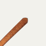 Close-up of the belt's rounded tip end, showing the wood-grain embossed tan leather texture with visible buckle holes.