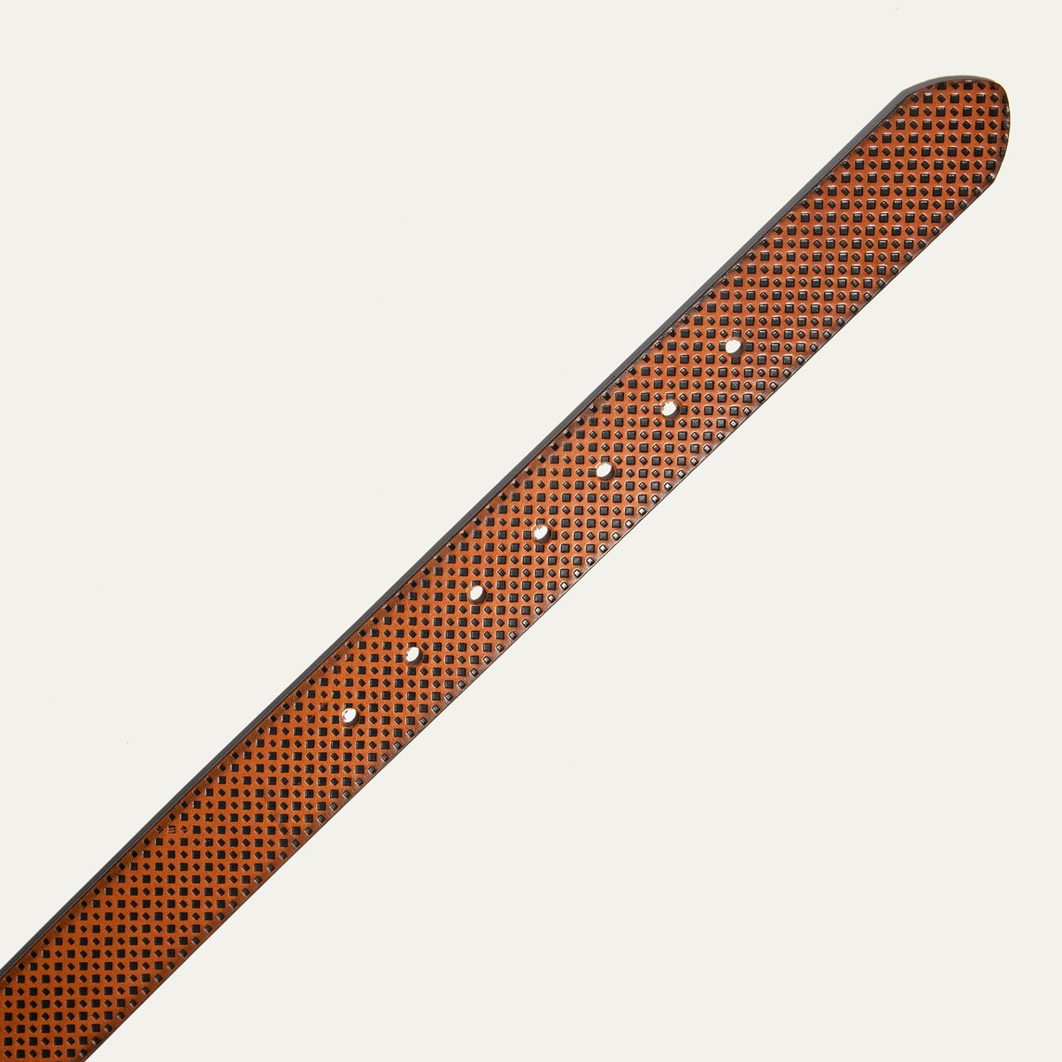 Close-up of the cognac brown diamond-embossed leather belt strap tip end with adjustment holes.
