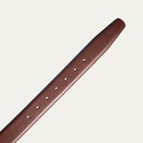 Close-up of the Will Leather Goods Glazed Calfskin Belt strap in cognac brown, showing the row of adjustment holes and the smooth glazed leather finish.
