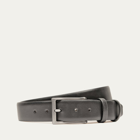 Will Leather Goods Glazed Calfskin Belt in black, coiled flat showing the polished leather strap, brushed silver prong buckle, and keeper loop, on a white background.