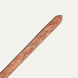 Close-up of the Hand-Tooled Morning Glory Jean Belt strap tip in natural tan leather, showing the hand-tooled floral scrollwork and row of adjustment holes.