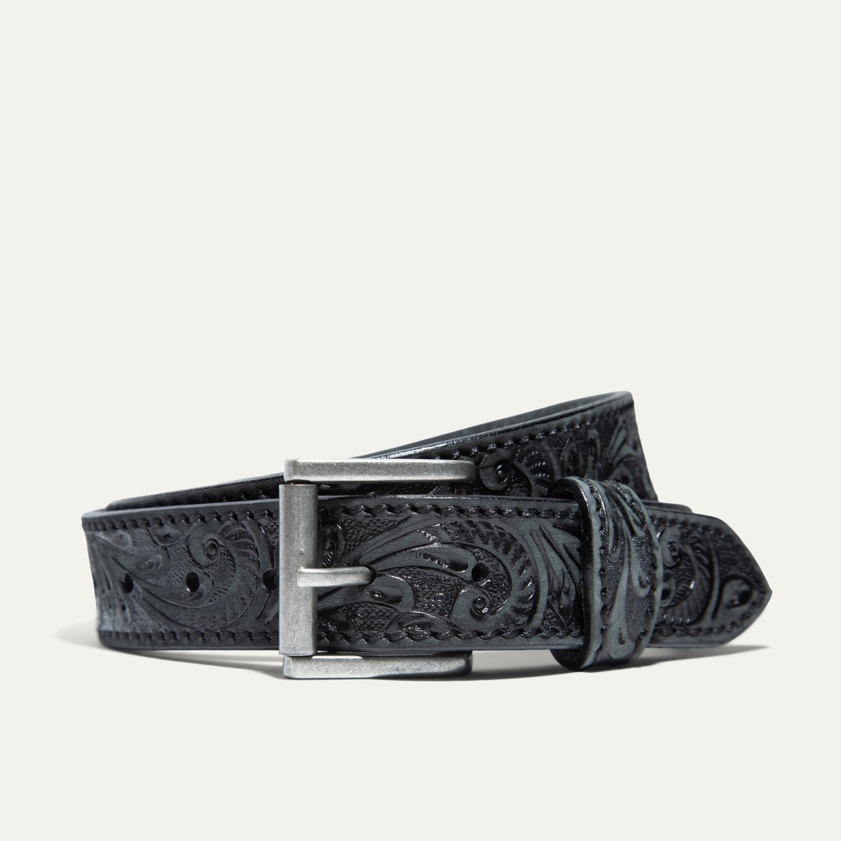 Hand-Tooled Morning Glory Jean Belt by WILL Leather Goods in black leather with a hand-tooled floral pattern and antique nickel buckle, coiled front product view on a white background.