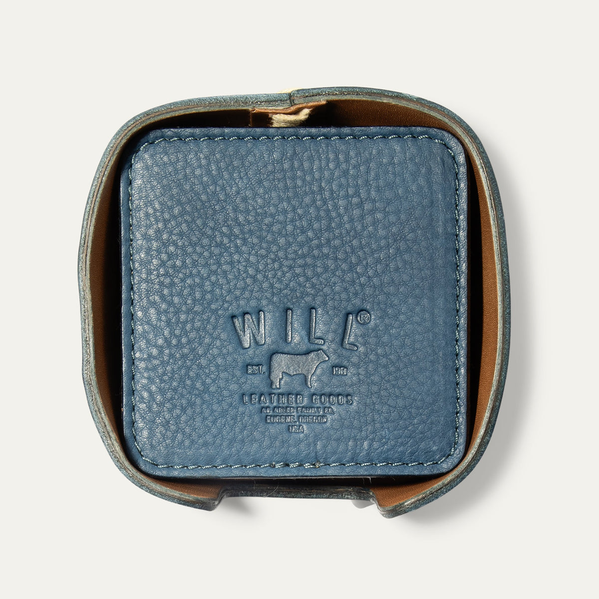 Open round leather holder for the Set of Eight Coasters in slate blue pebbled leather, showing the embossed WILL logo, on a white background.