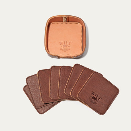 Open round leather holder for the brown Set of Eight Coasters showing its tan interior and embossed WILL Leather Goods logo, with all eight brown coasters fanned out below on a white background.