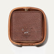 Will Leather Goods Set of Eight Coasters in brown pebbled leather, shown stacked inside the open round leather holder with embossed WILL logo, on a white background.