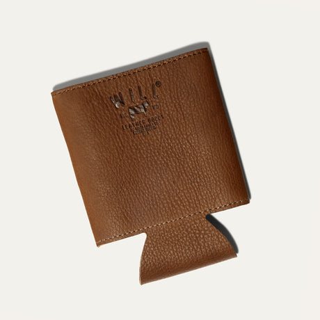Will Leather Goods Leather Bottle & Can Holder in cognac leather, empty koozie shown at an angle with the embossed WILL cattle-brand logo, on a white background.