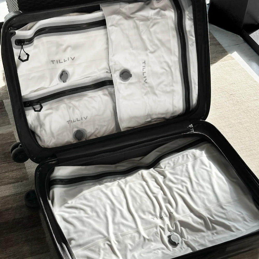 Open hardside carry-on packed with four white TILLIV Compak vacuum packs
