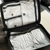 Open hardside carry-on packed with four white TILLIV Compak vacuum packs