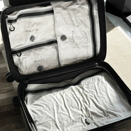 Open hardside carry-on packed with four white TILLIV Compak vacuum packs