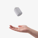 A white TILLIV Nano Pump caught in mid-air above an open palm, showing how light it is