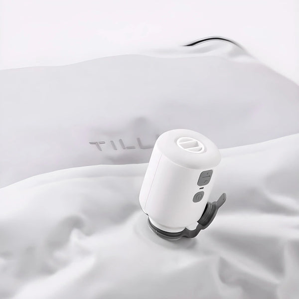 A TILLIV Nano Pump seated on the one-way valve of a white vacuum pack, drawing the air out