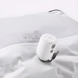 A TILLIV Nano Pump seated on the one-way valve of a white vacuum pack, drawing the air out