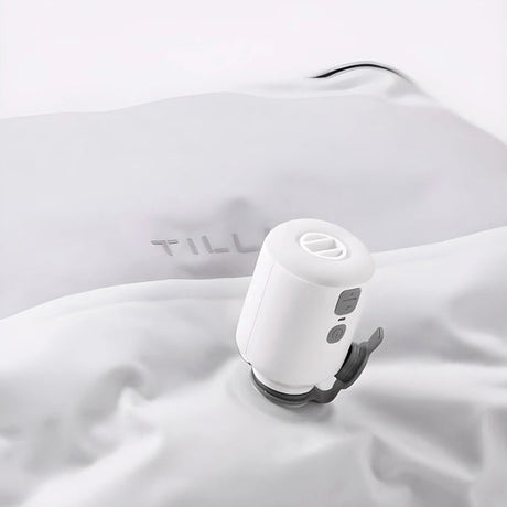 A TILLIV Nano Pump seated on the one-way valve of a white vacuum pack, drawing the air out