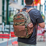 Lifestyle photo of a man walking down a city sidewalk wearing the green digital camo Canvas + Leather Backpack with brown leather straps and trim.