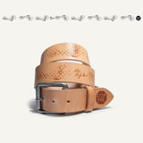 Natural tan leather belt coiled upright, showing the gunmetal roller buckle and brown waffle-tread emboss pattern along the strap, with a STOP PRE tab stamped near the tip