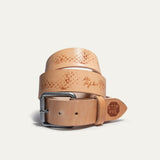 Close angle of the coiled natural tan leather belt highlighting the gunmetal roller buckle, waffle-tread emboss pattern, and STOP PRE stamped tab near the pointed tip