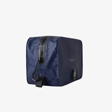 Three-quarter view of a Midnight Blue TILLIV Stak with water beaded across its zipper panel, showing the water-resistant surface